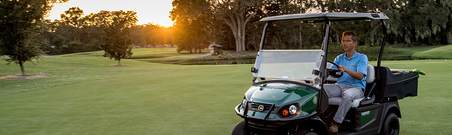 Man riding in a green E-Z-GO® golf cart on a golf course.